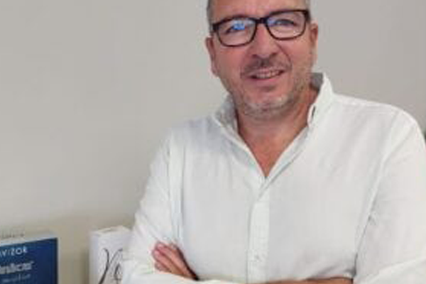 Eduardo Dutrey, responsable de preimpresión de Leca Graphics España, con camisa blanca y brazos cruzados frente al logotipo de Lecagraphics.