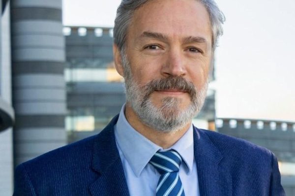 Retrato de Agustín Canales, director de Healthcare de Grupo Lantero, con traje azul frente a un edificio corporativo.